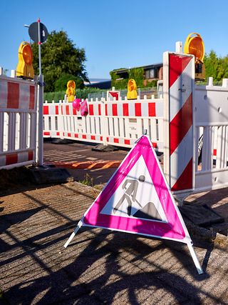 Baustellenschild mit weißen Absperrzäunen, mit weiß-roten Streifen, gelben Warnlichtern