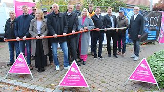 Die Beteiligten halten an der Baustelle ein Stück Speedpipe in den Händen. 