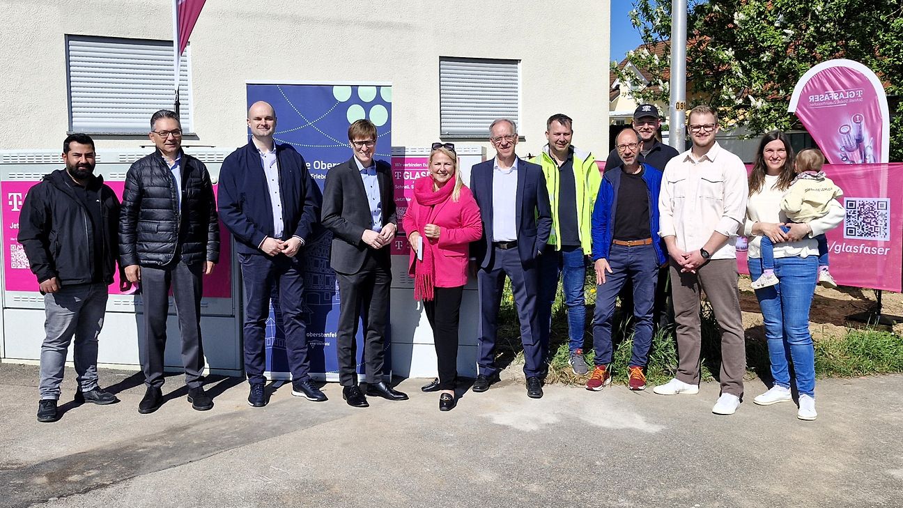 Die Teilnehmenden stehen an der Straßenecke vor einem Verteilerkasten. Im Hintergrund Banner von Telekom und Zweckverband. 