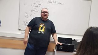 Ein Mann, neben ihm ein PC. Im Vordergrund eine ZuhörerinEin Mann, neben ihm ein PC. Im Vordergrund eine Zuhörerin