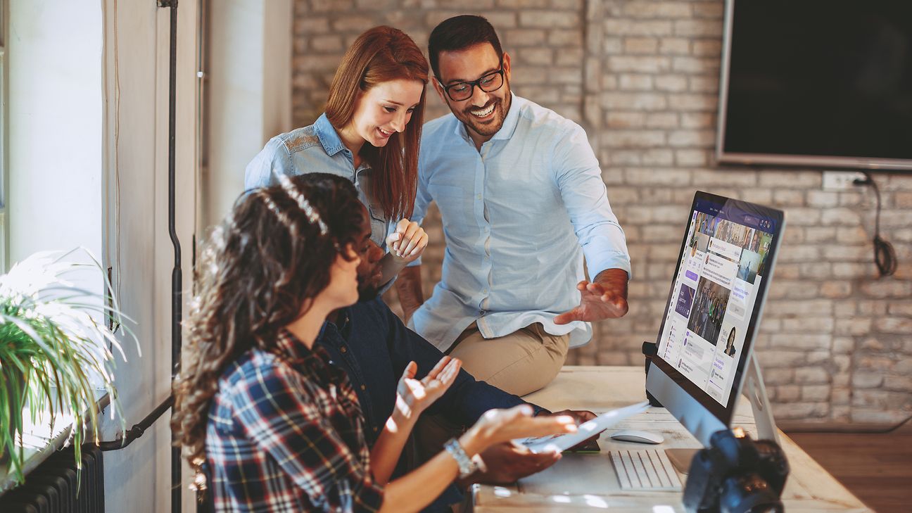 Four employees at a computer.