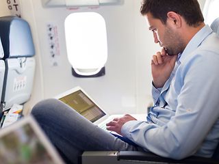 Inflight: Mann sitzt im Flugzeug am Laptop