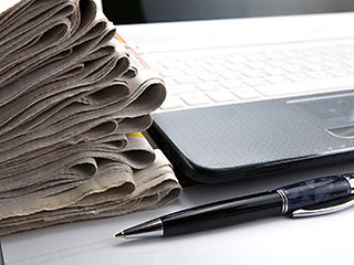 Alte und neue Medien: Zeitungen und Laptop