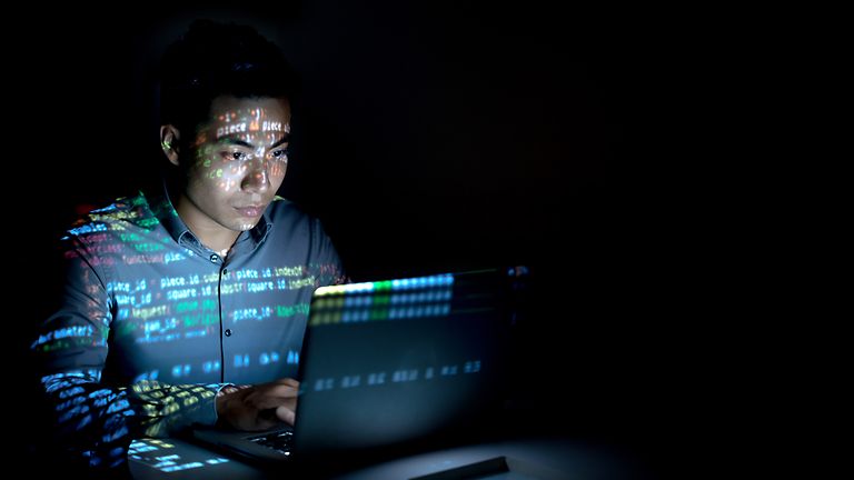Zahlenreihen werden auf einen Mann vor einem Laptop projiziert