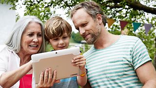 Grandmother, father and son looking at tablet computer.