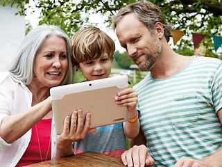 Grandmother, father and son looking at tablet computer.