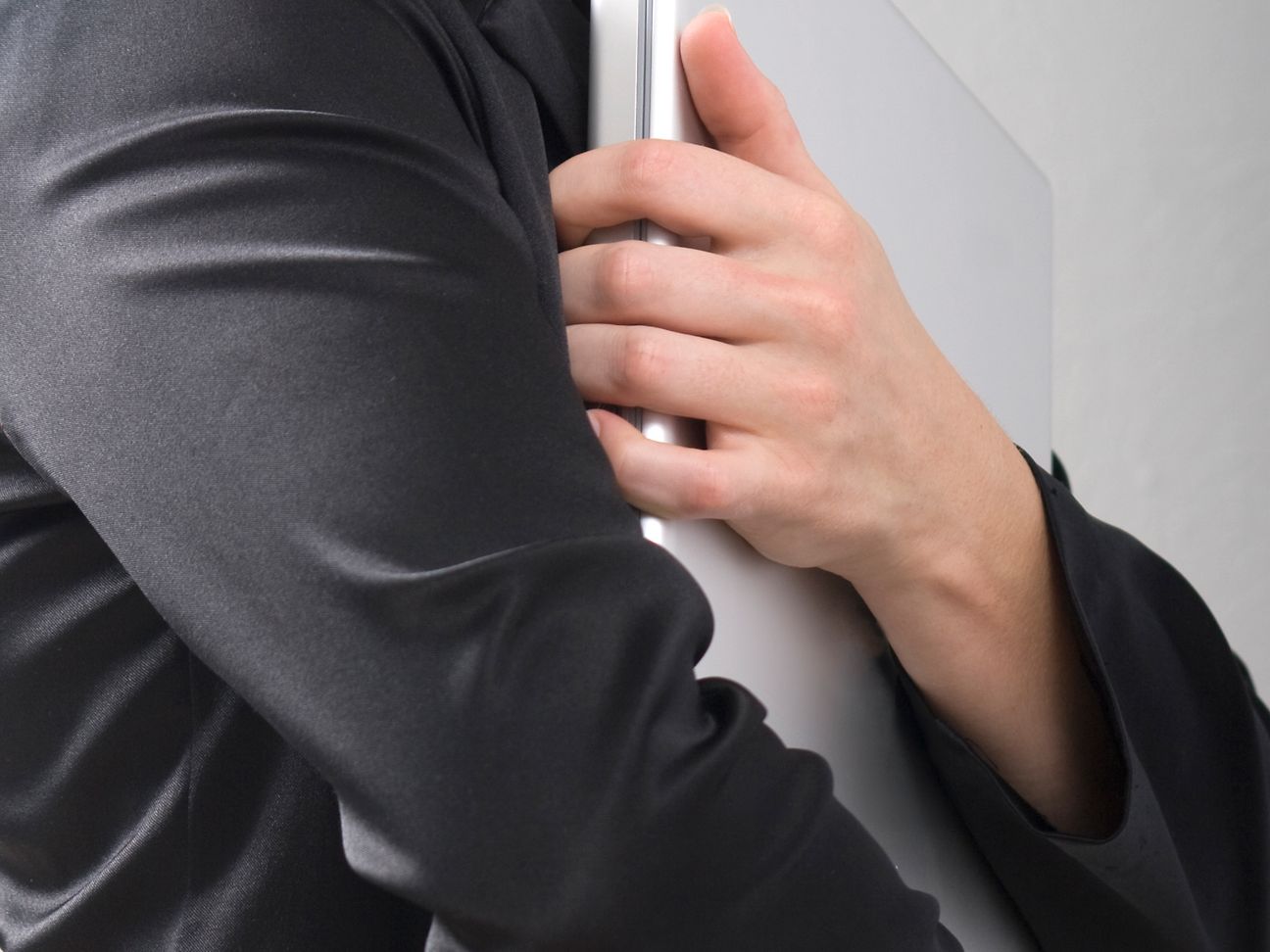 A man is clasping his laptop protoctively.