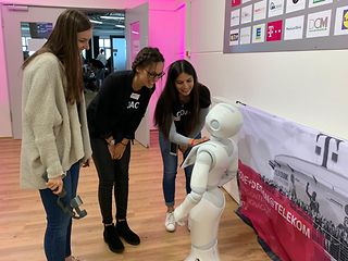 3 Studentinnen die sich mit einem Roboter unterhalten