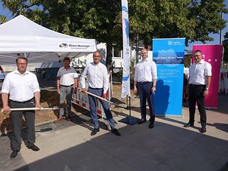 Vertreter der Gemeinde, der Telekom und der Gigabitregion Stuttgart stehen mit symbolischen Schaufeln vor einem Bauzelt.