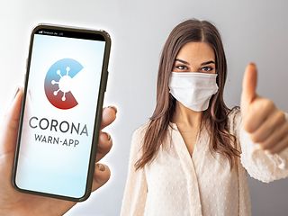 Eine Frau zeigt Daumen hoch für die Corona-Warn-App