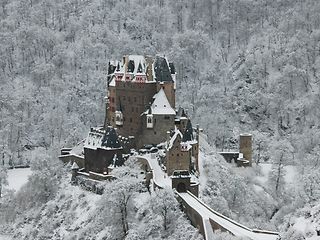 Ansicht der Burg Eltz im tief verschneiten Winterwald.