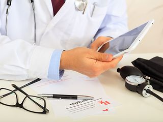 Ein Arzt hält ein Tablet in den Händen