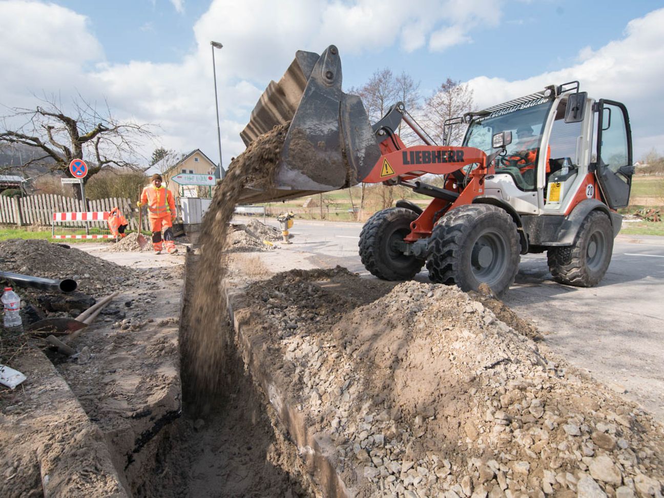 Ein Bagger schüttet Erde in eine Baugrube.