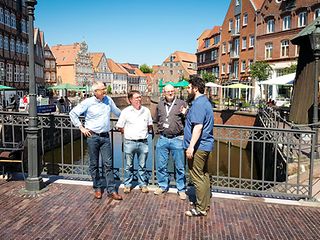 Vier Männer unterhalten sich vor einer Stadtkulisse.