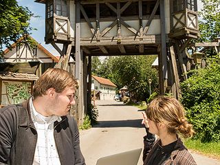 Ein Techniker mit Autorin Caroline Eichhorn vor dem Eingangstor in Kaltenberg.