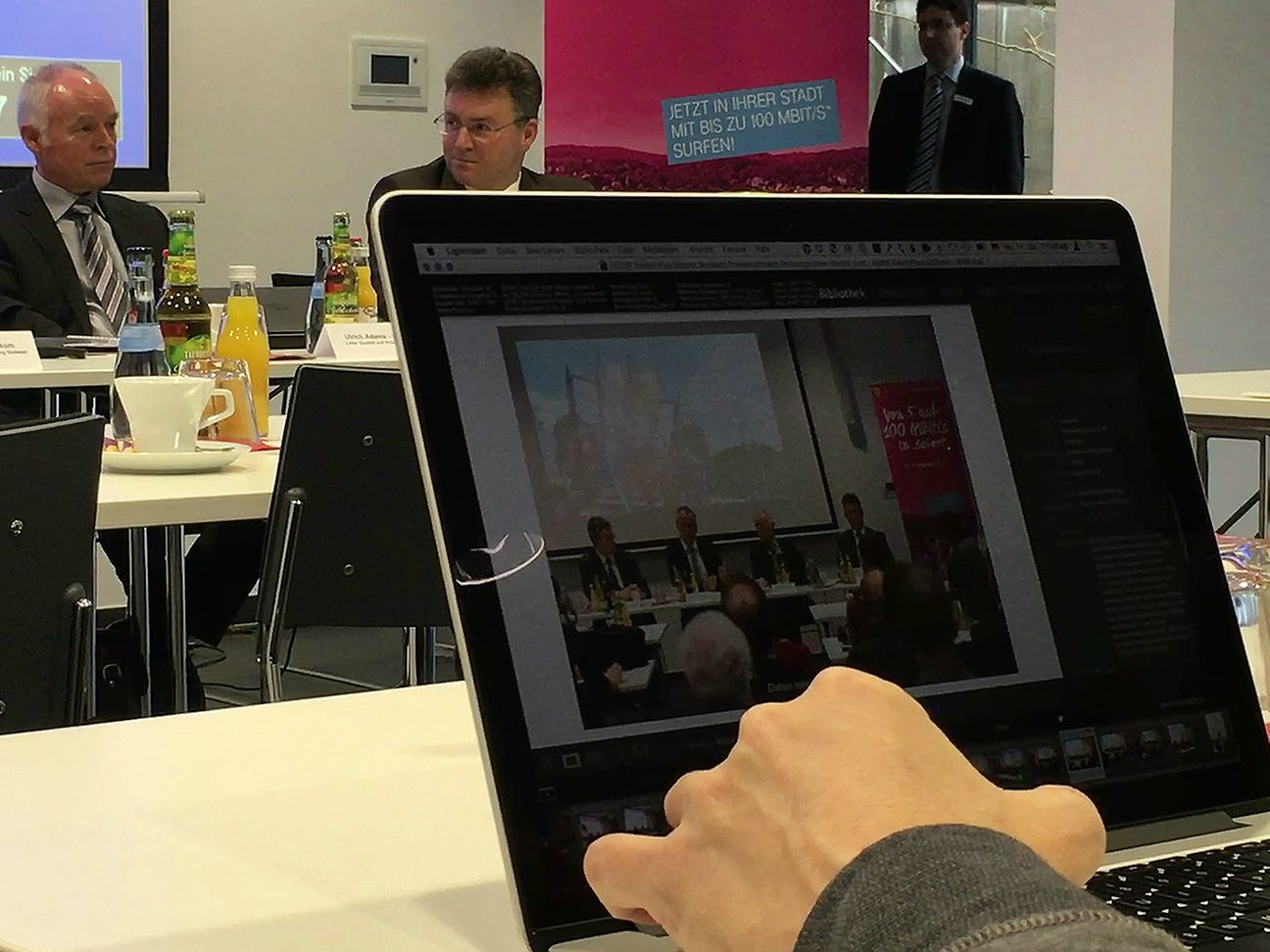 Blick über einen Laptop hinweg auf Ulrich Adams.